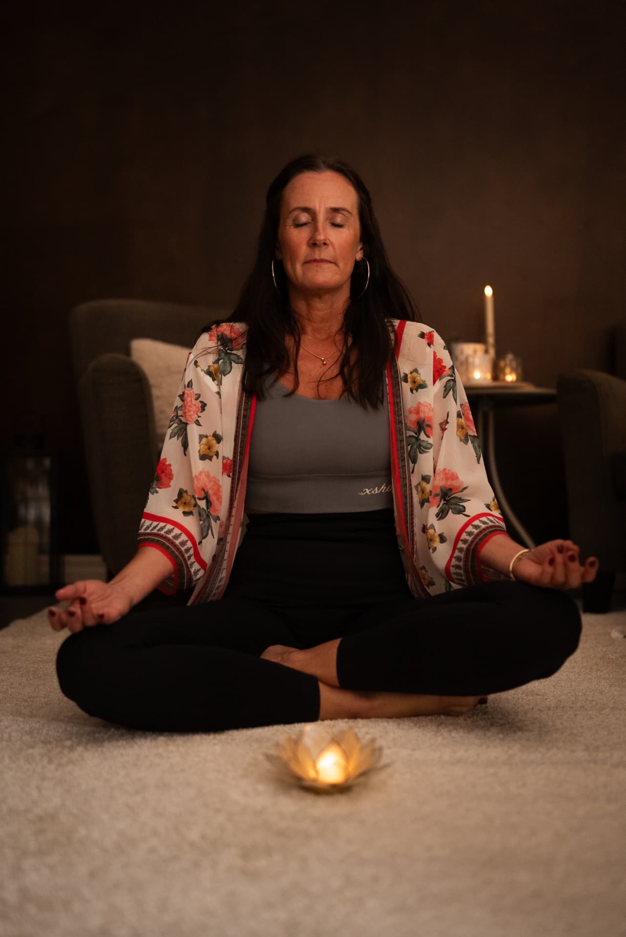 Sara i stilla meditation med ett tänt ljus framför sig